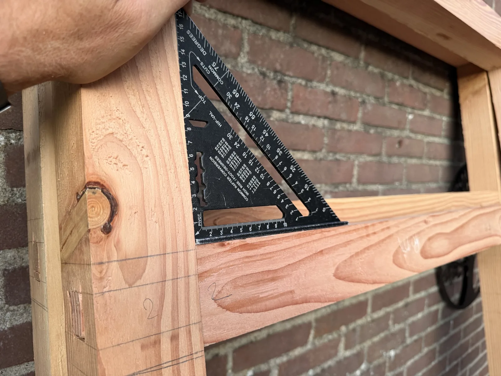 Hand met zwaaihaak die de haaksheid van de gemetselde opening controleert