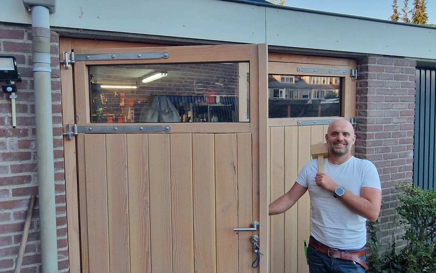 Bas Bartholomeus bij de afgebouwde garagedeuren in de avondzon