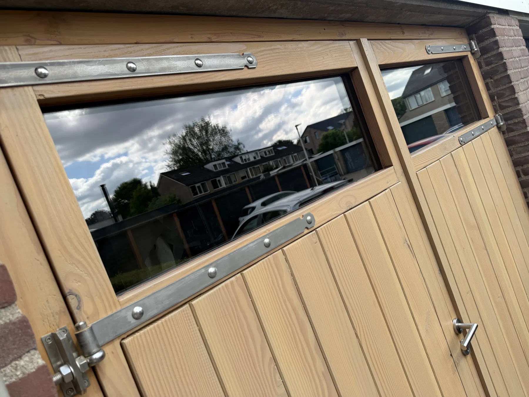 Een geopende vleugel schuin van opzij, met de straat weerspiegeld in het glas
